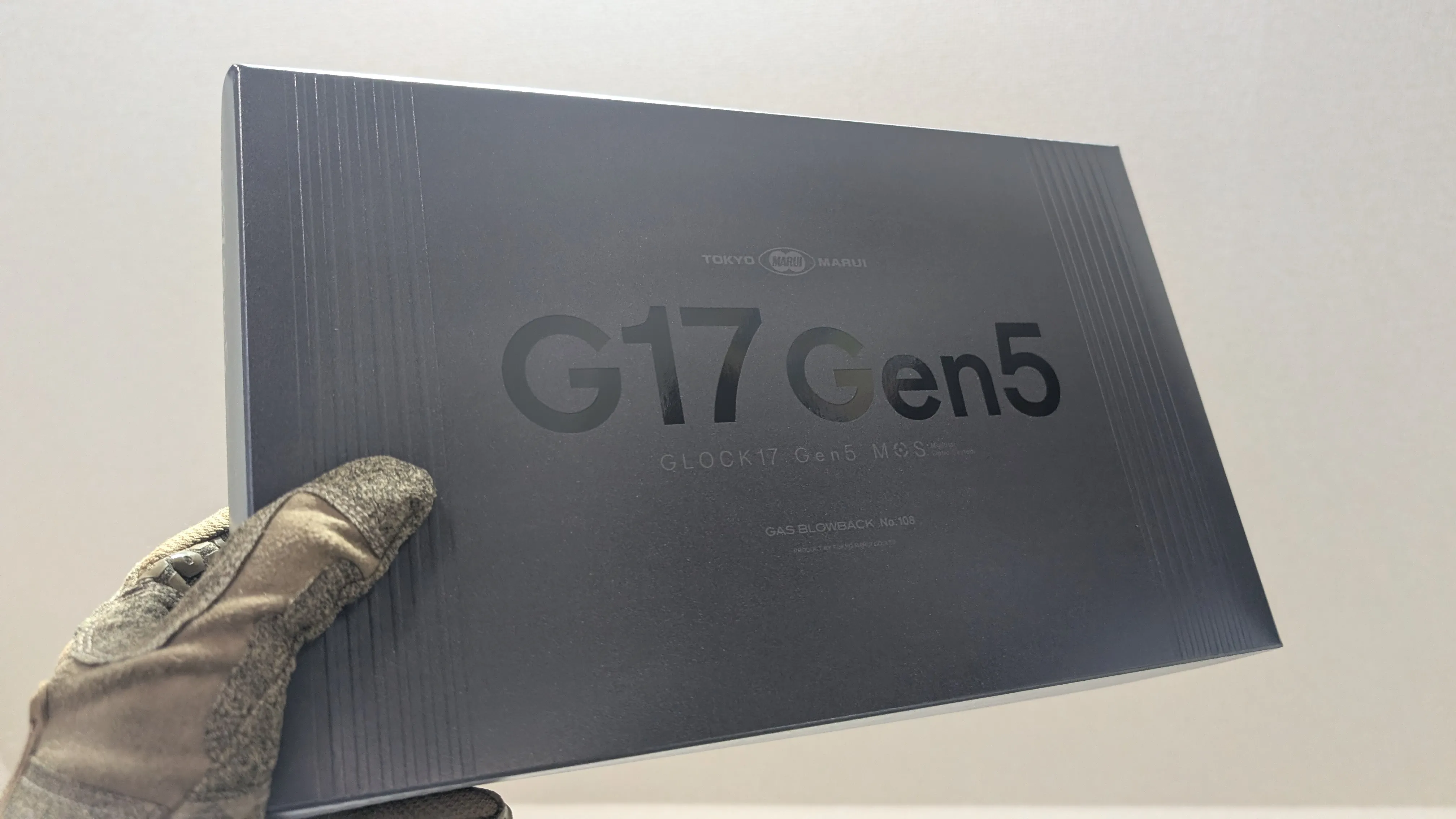 東京マルイ G17 Gen5 の箱（タクティカルグローブをはめた手で持っている）